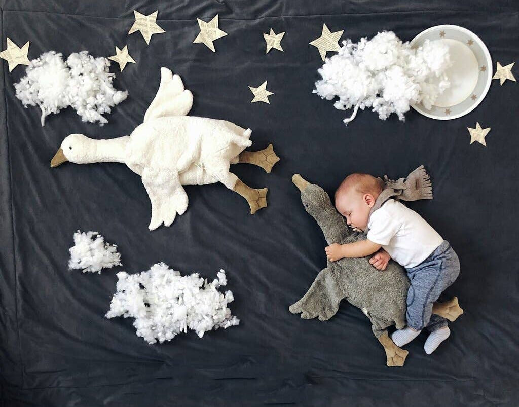 Child playing with stuffed animals on a dark surface with star and cloud decorations