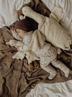 Child wrapped in a blanket with plush toys on a bed